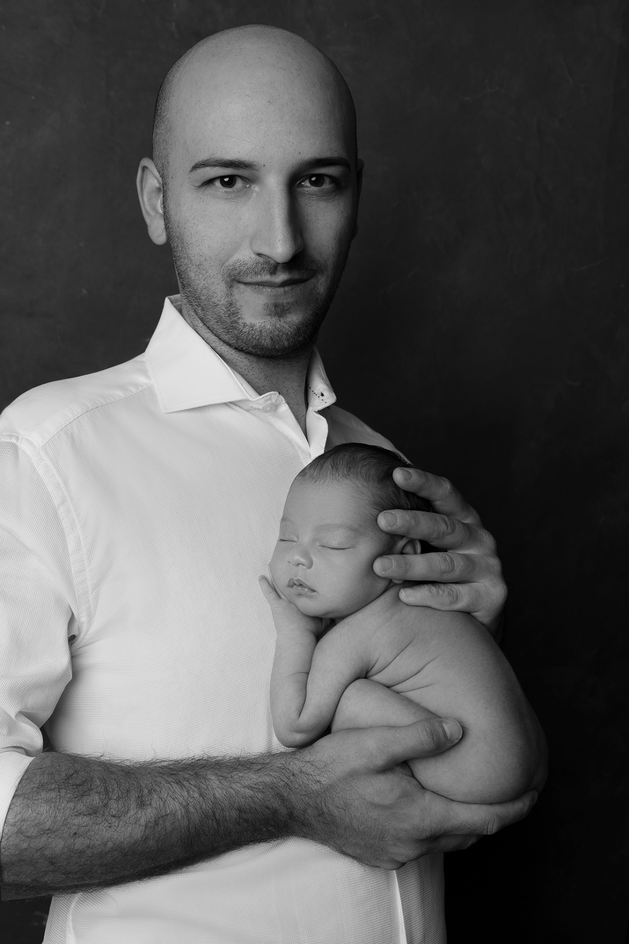 Ritratto in bianco e nero di padre che culla la neonata addormentata, realizzato da Claudia Spaziani fotografa a Bologna. Fotografia che esalta amore e protezione