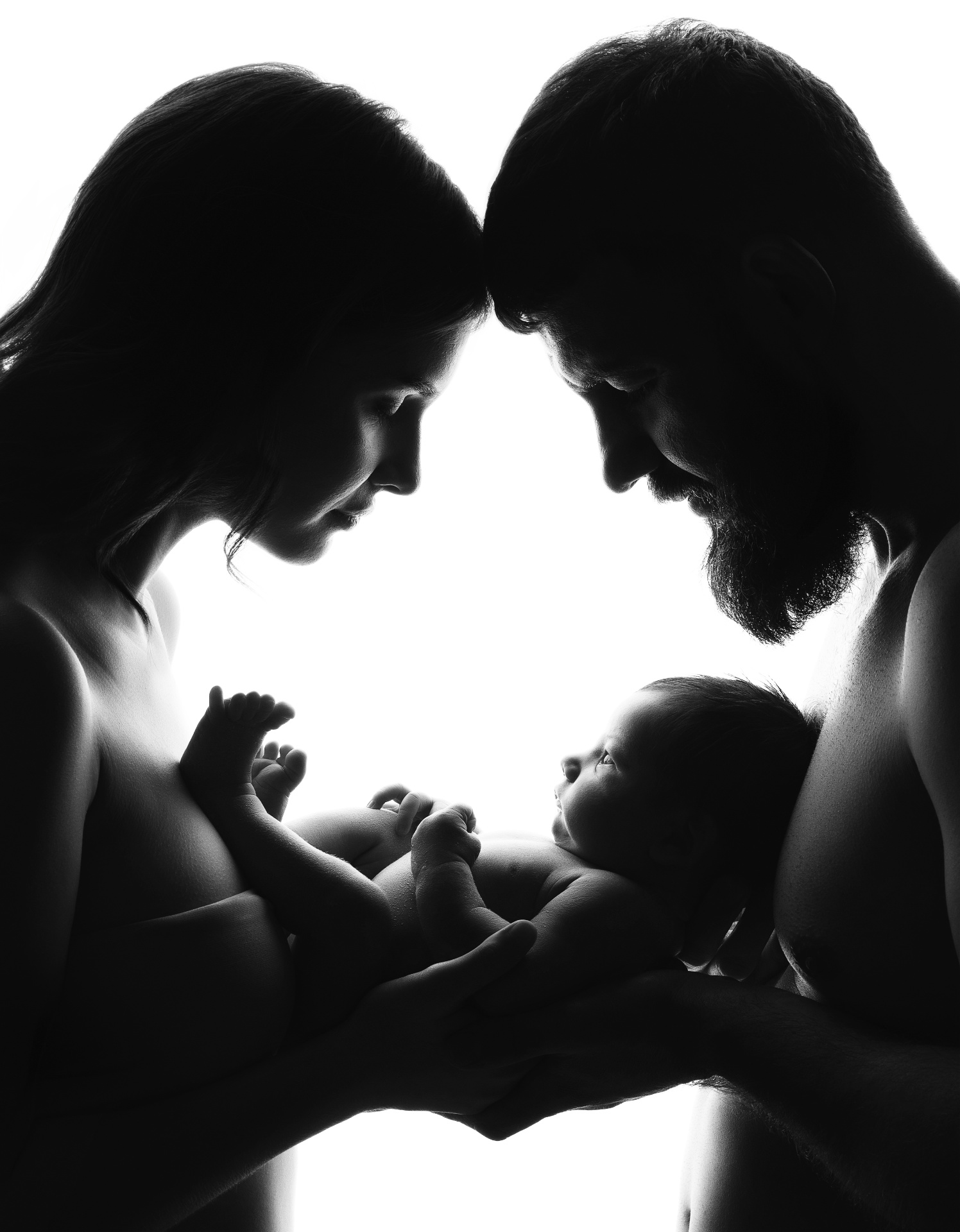 Claudia Spaziani fotografa newborn a Bologna: ritratto in bianco e nero di coppia che tiene il neonato tra le mani.