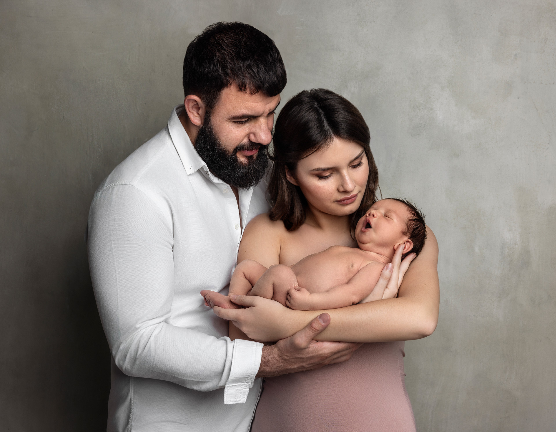 Servizio fotografico newborn a Bologna di Claudia Spaziani: ritratto di famiglia con mamma, papà e neonato in braccio.