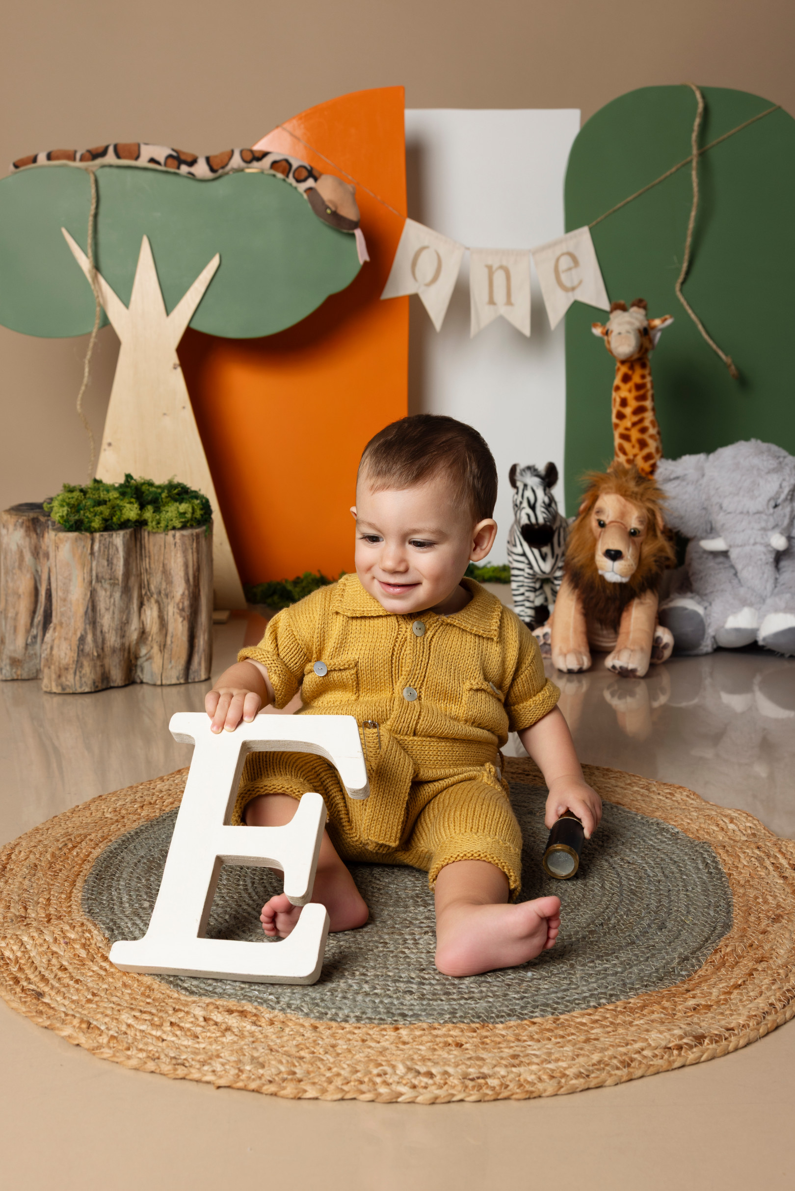 Bambino seduto accanto alla lettera di legno “E” sul set smash cake a tema safari — Claudia Spaziani, Bologna.