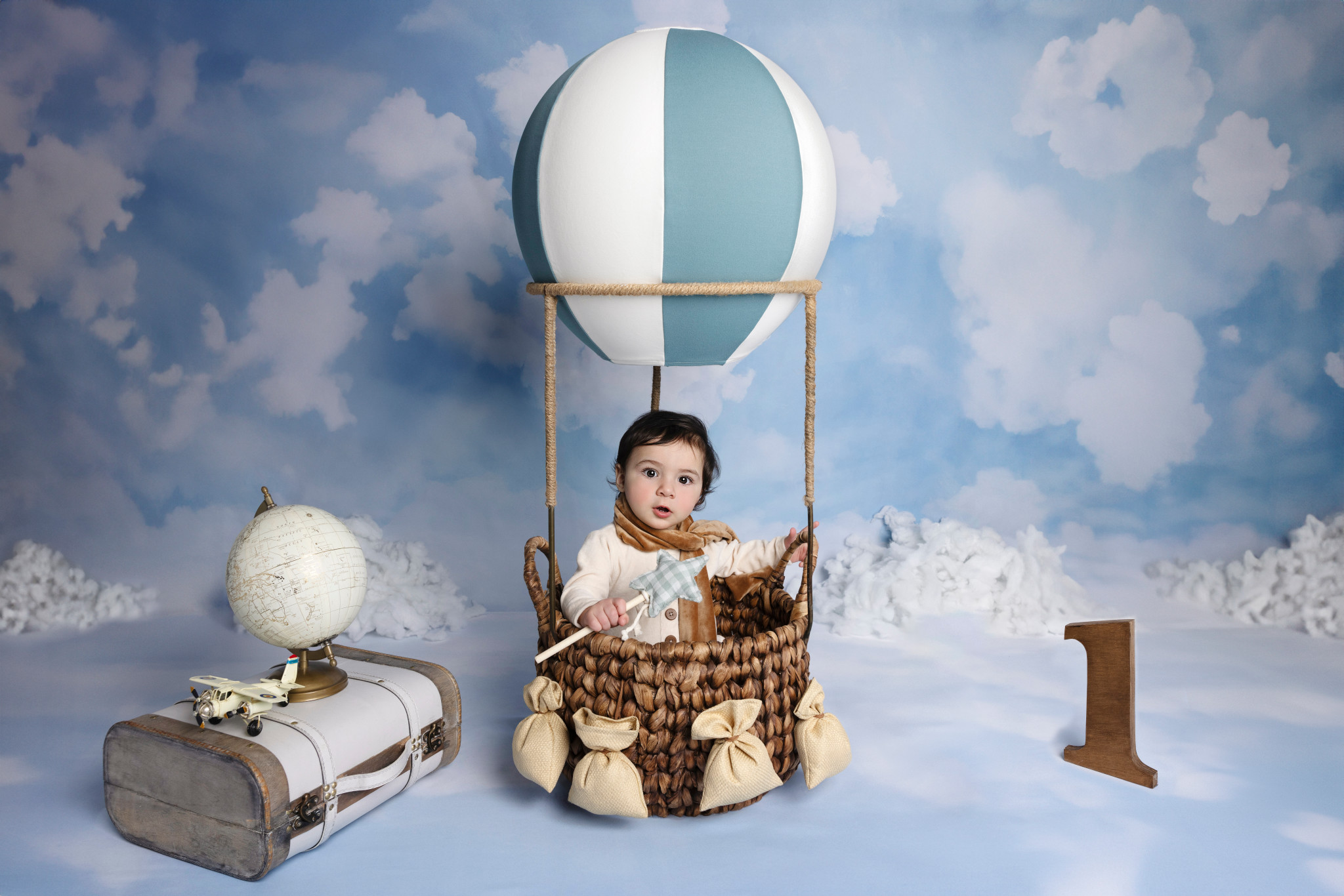 Bambino nella navicella della mongolfiera con valigia vintage e mappamondo — set a tema viaggio, fondale cielo, Bologna.