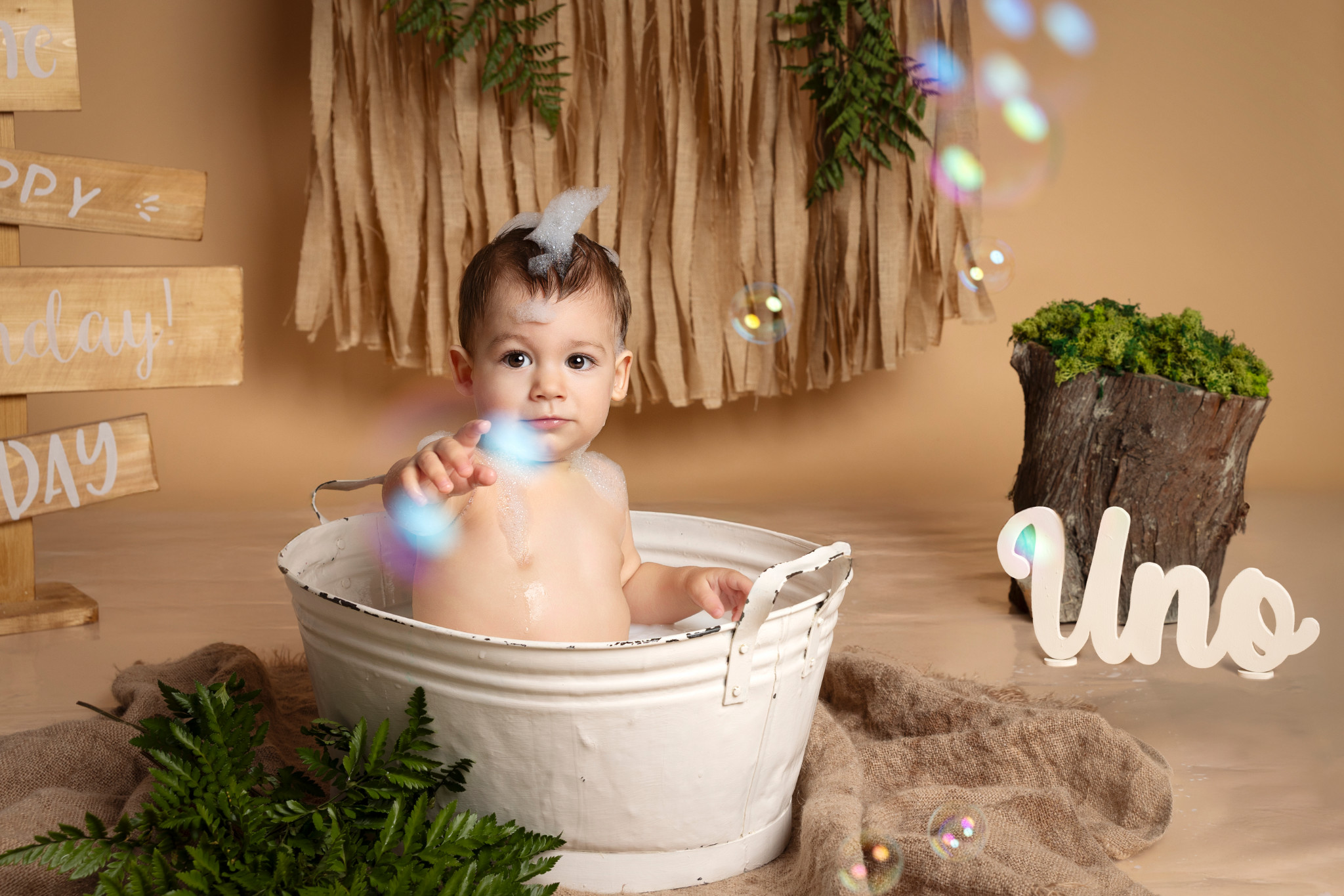 Bambino nella vasca indica la scritta “Uno” tra le bolle di sapone — sessione splash boho a Bologna.