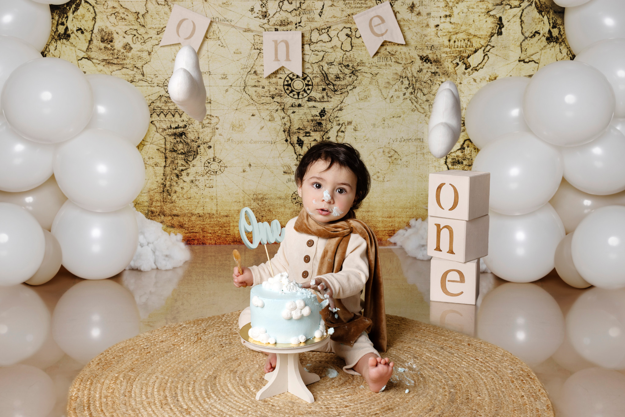 Bambino dietro la torta azzurra con i cubi di legno “one” accanto — smash cake a tema aviatore a Bologna.