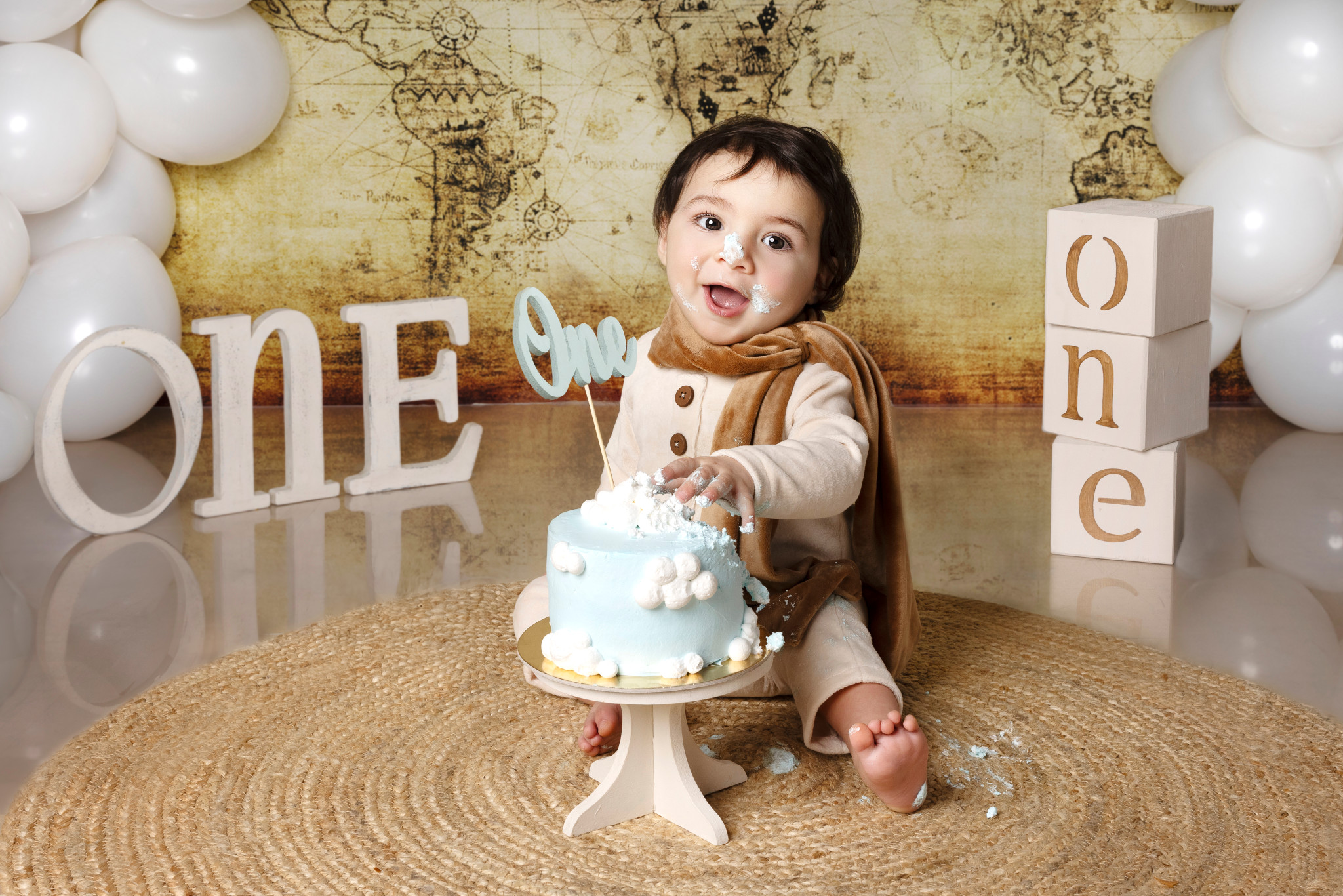Bambino dietro la torta azzurra con lettere “ONE” e cubi “one” — smash cake a tema aviatore a Bologna.