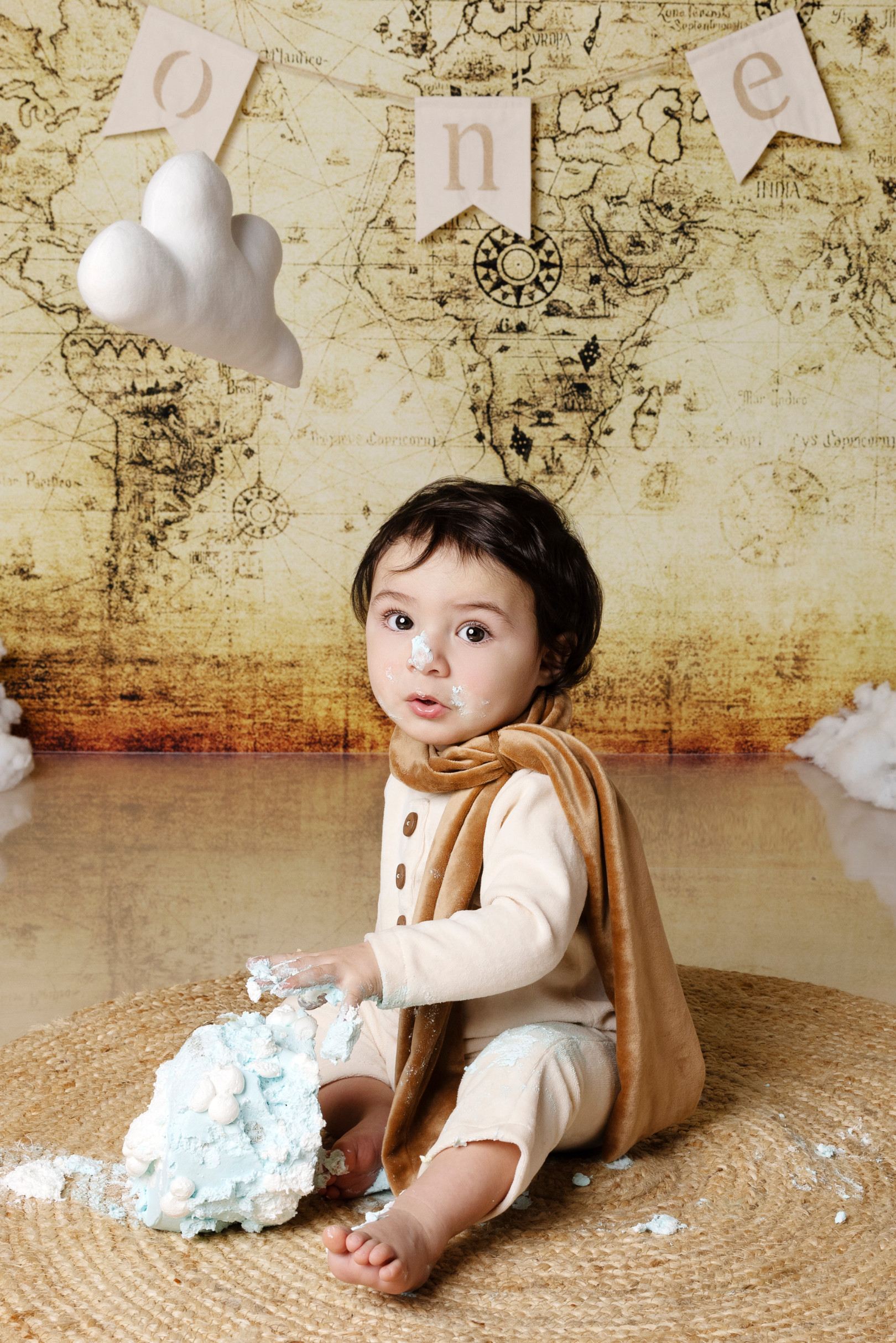Bambino distrugge la torta azzurra durante lo smash cake sul tappeto — fondale mappa antica, Bologna.