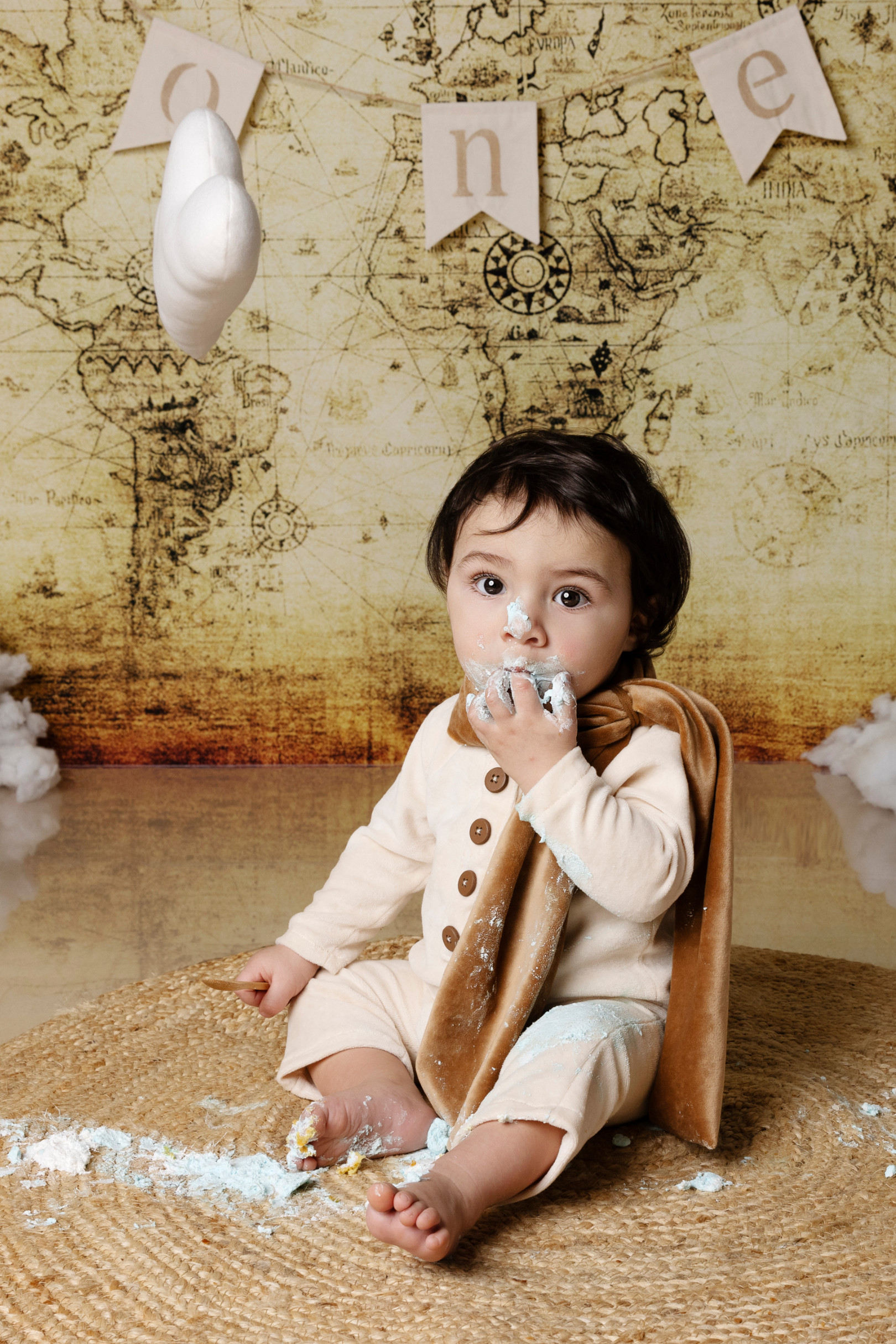 Bambino assaggia la torta azzurra durante lo smash cake, sciarpa da aviatore — fondale mappa, Bologna.