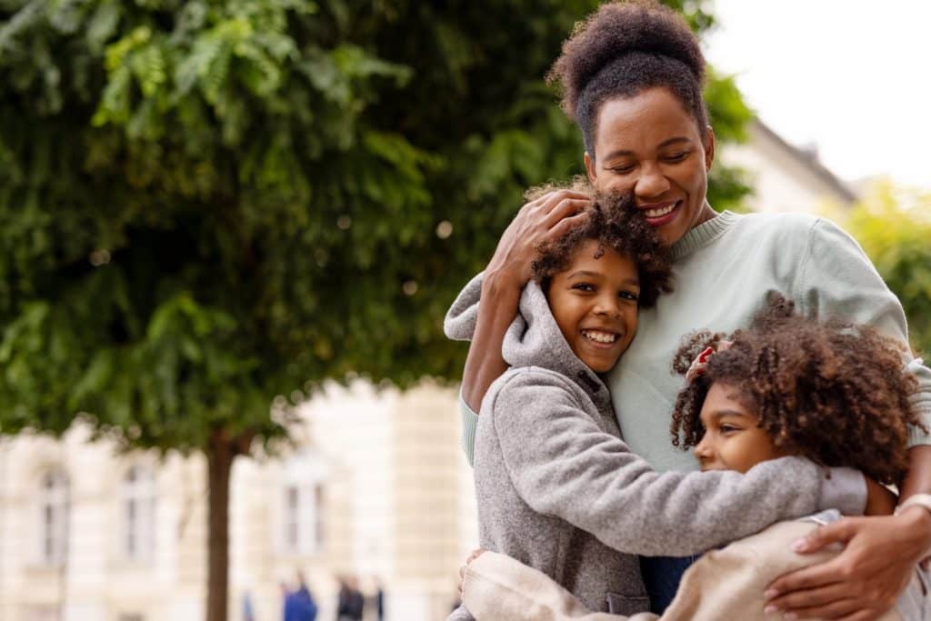 Mother hugging two children outdoors