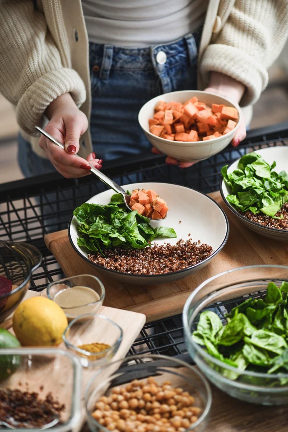 Hands preparing a fresh salad and grain bowl