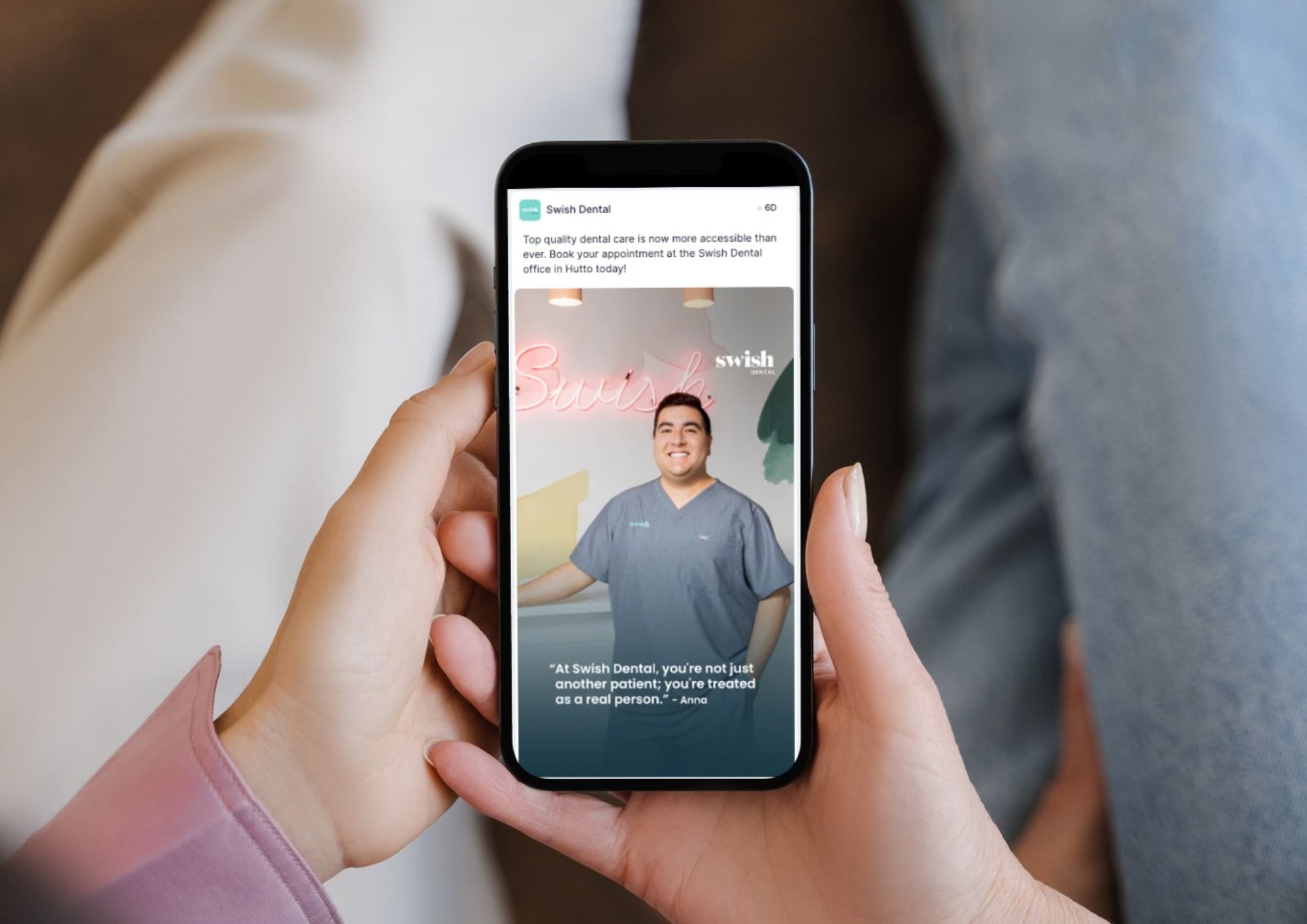 A person holding a smartphone displaying a social media post from Swish Dental with a smiling dental professional in scrubs and the quote: 'At Swish Dental, you're not just another patient; you're treated as a real person.'