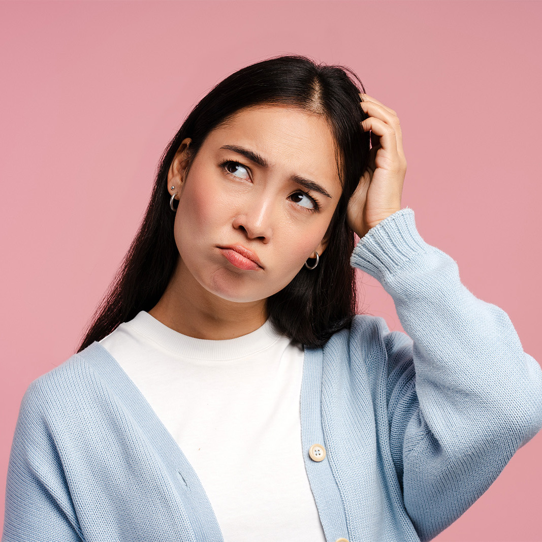 A confused woman scratching her head