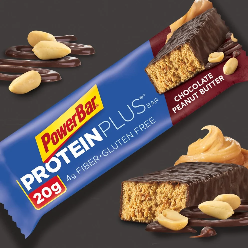 PowerBar Protein Plus bar in chocolate peanut butter flavor with 20g protein, 4g fiber, and gluten free, shown with peanuts, peanut butter, and chocolate drizzle on a dark background.