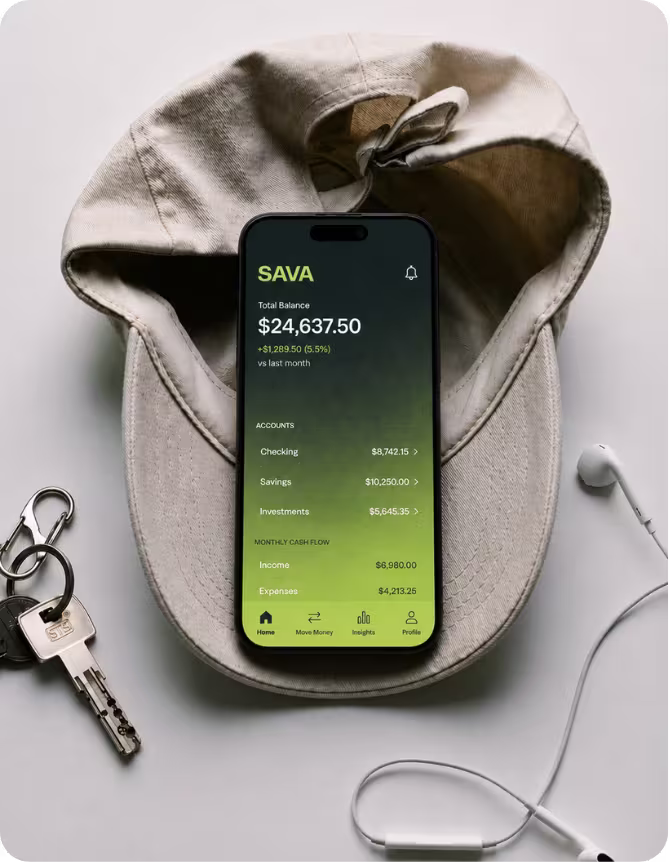 A smartphone displaying the SAVA app with a total balance of $24,637.50 and account details, placed inside a beige baseball cap, next to a house key and white earbuds on a light surface.