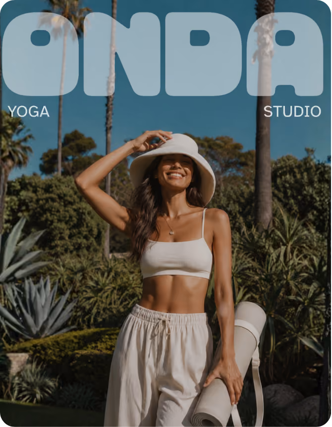 Smiling woman in light casual yoga attire and a wide-brimmed hat holding a rolled-up yoga mat, standing outdoors with palm trees and plants in the background under a clear blue sky.