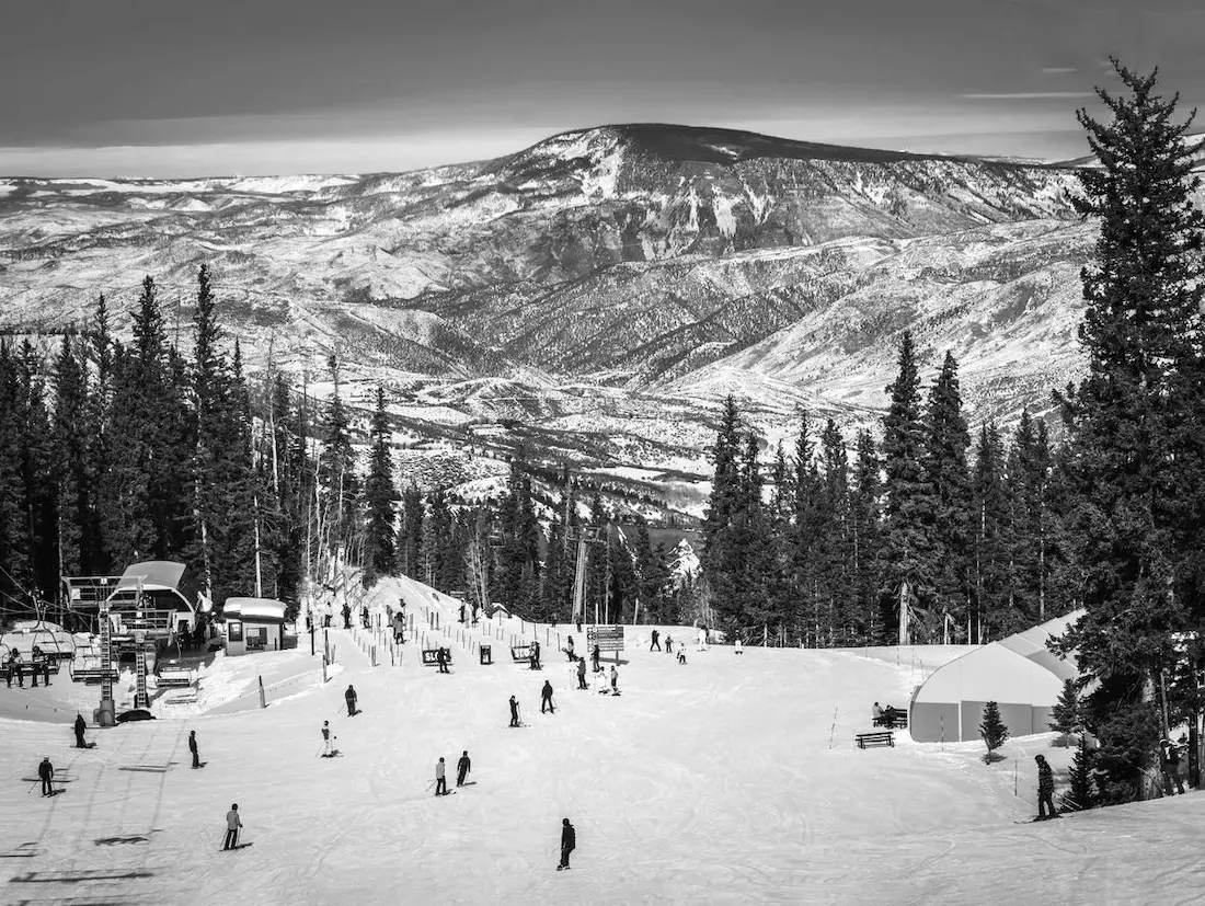 Skiers at a mountain ski lift and lodge