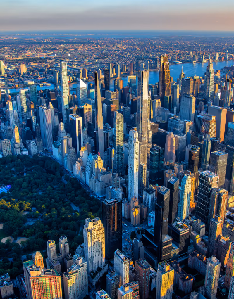 Aerial view of New York City skyline with Central Park on the left during sunset.