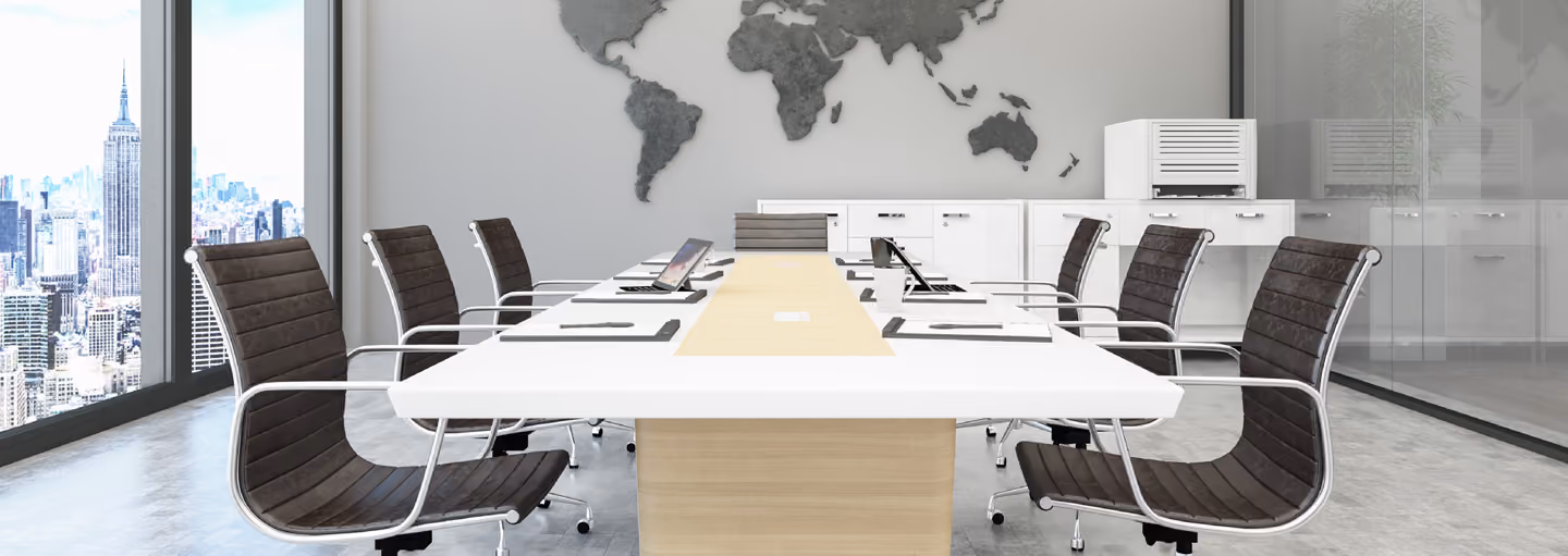 Modern conference room with long table, black chairs, laptops, and a world map wall decoration.