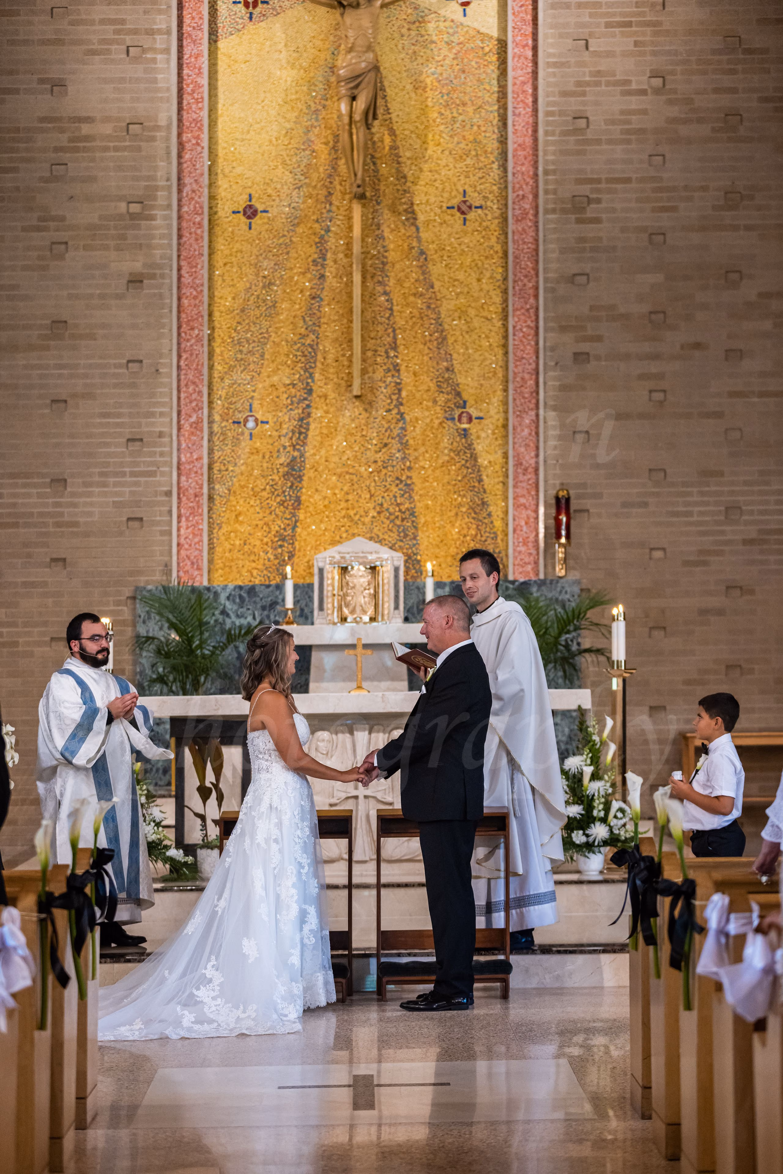 Bride and groom holding hands exchanging vows at the altar during a Catholic church wedding