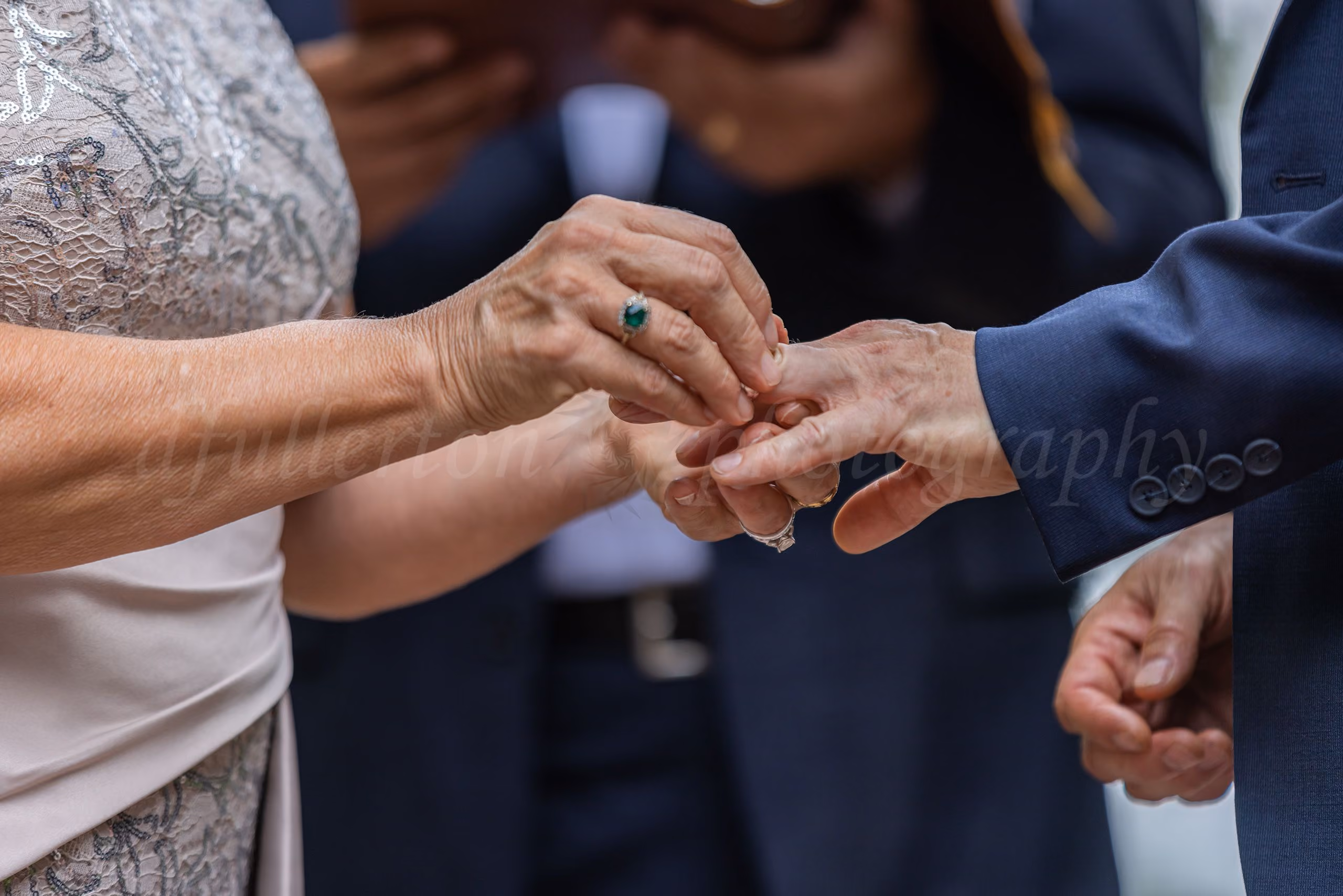 Close-up of hands during a wedding ring exchange at an outdoor ceremony