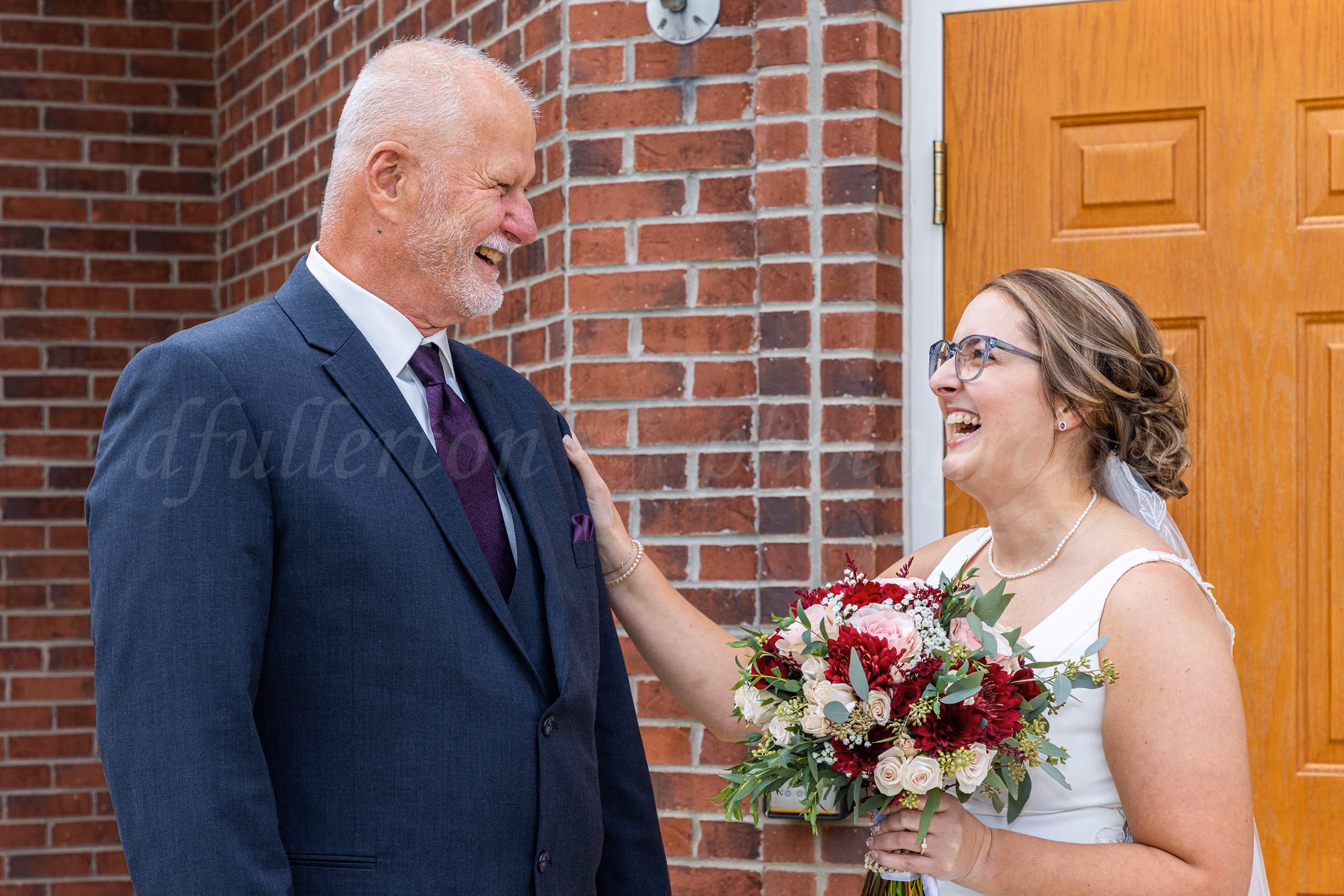 Bride laughing with her father during their first look outside a brick church