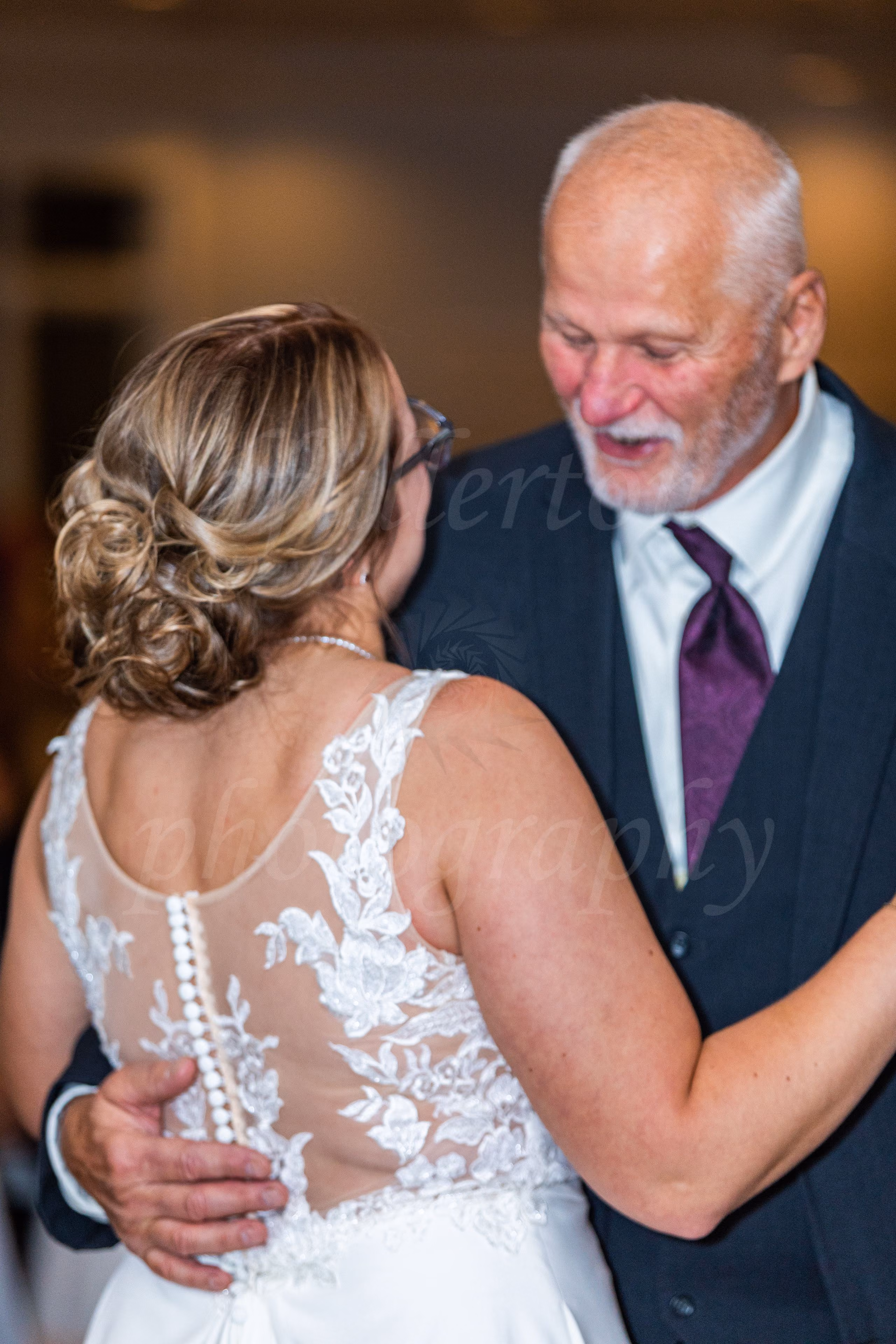 Bride sharing a father-daughter dance, smiling at each other at the reception