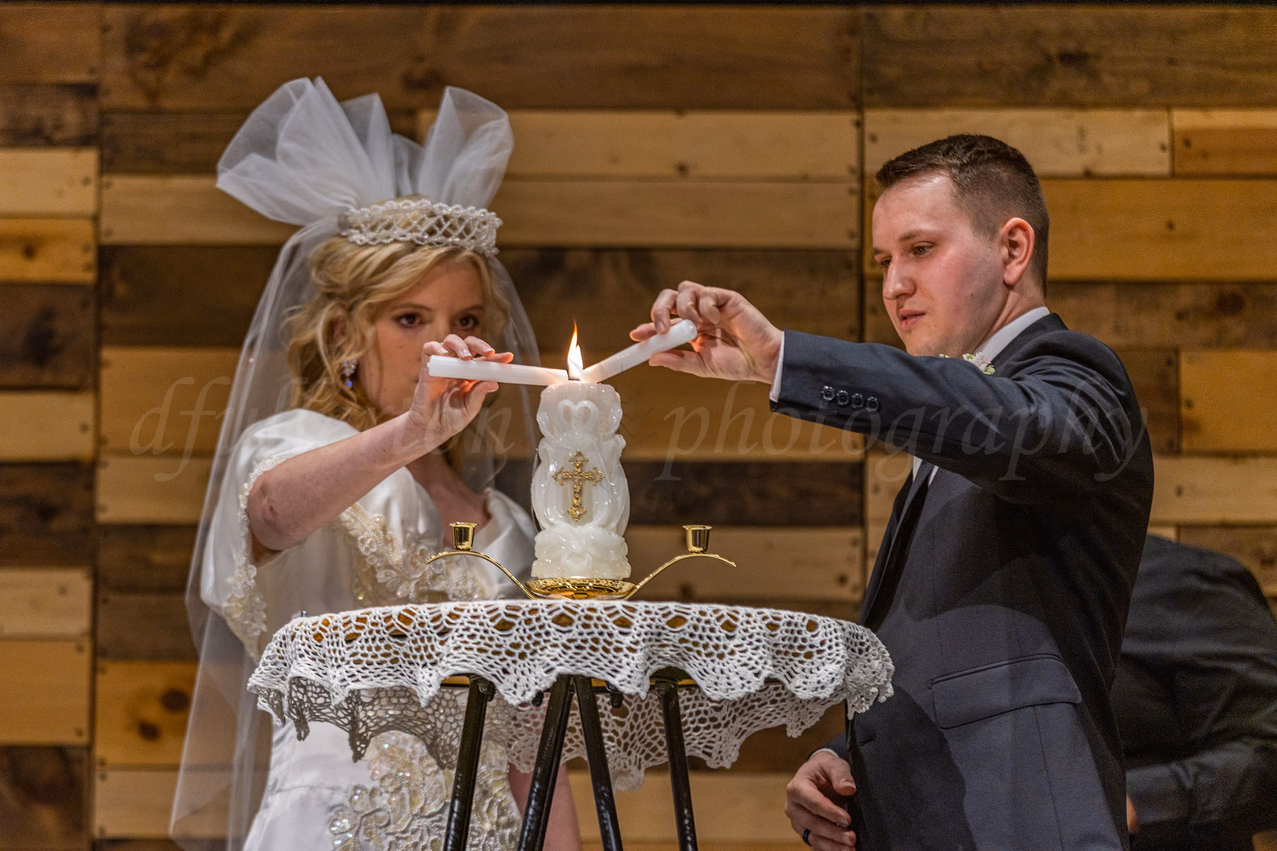Bride and groom lighting a unity candle together at their wedding ceremony.