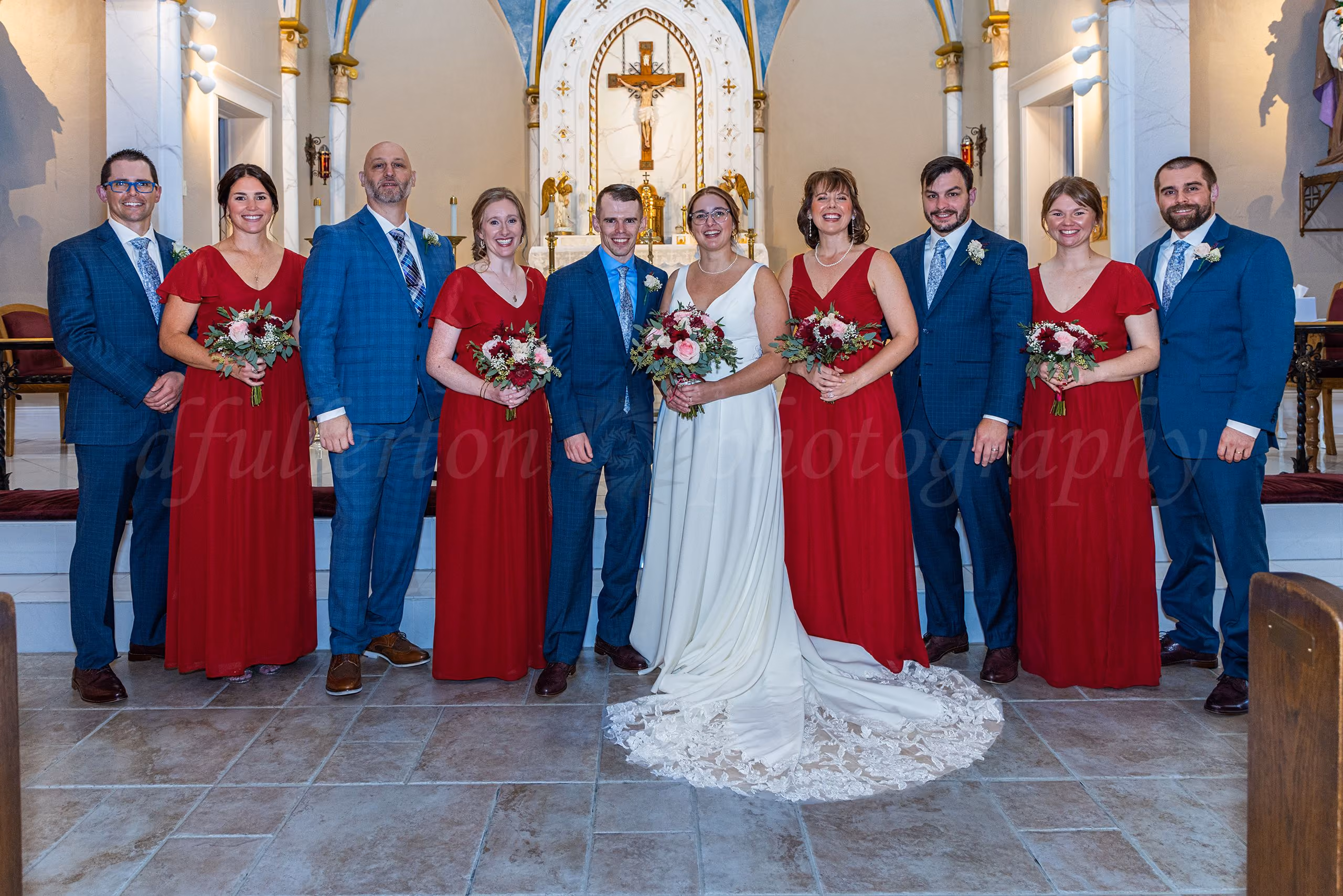 Wedding party at the church altar, bridesmaids in red dresses and groomsmen in blue suits