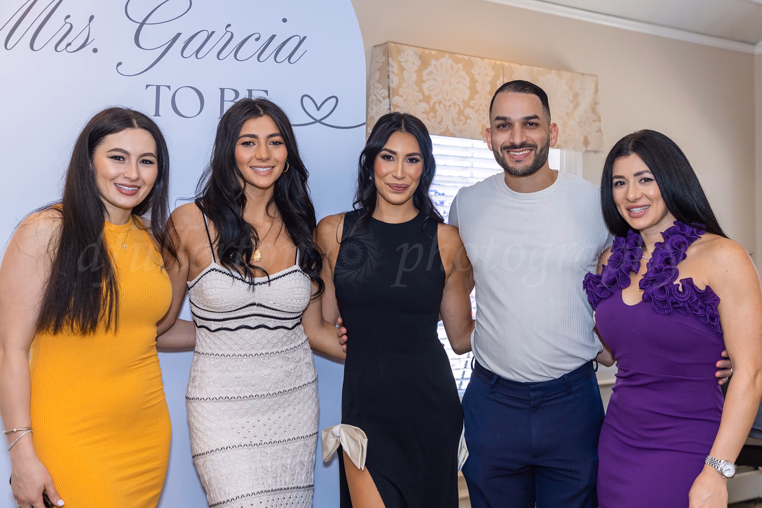 Group photo at a bridal shower in front of a Mrs. Garcia To Be sign