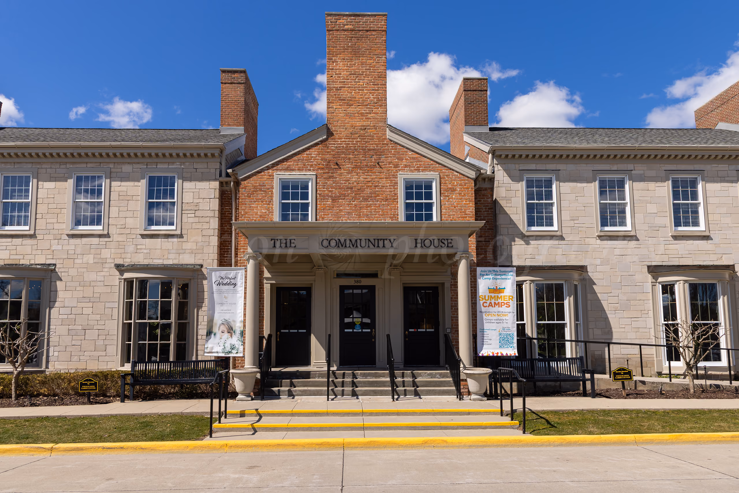 Exterior of The Community House wedding venue, a brick and stone building with a banner advertising weddings