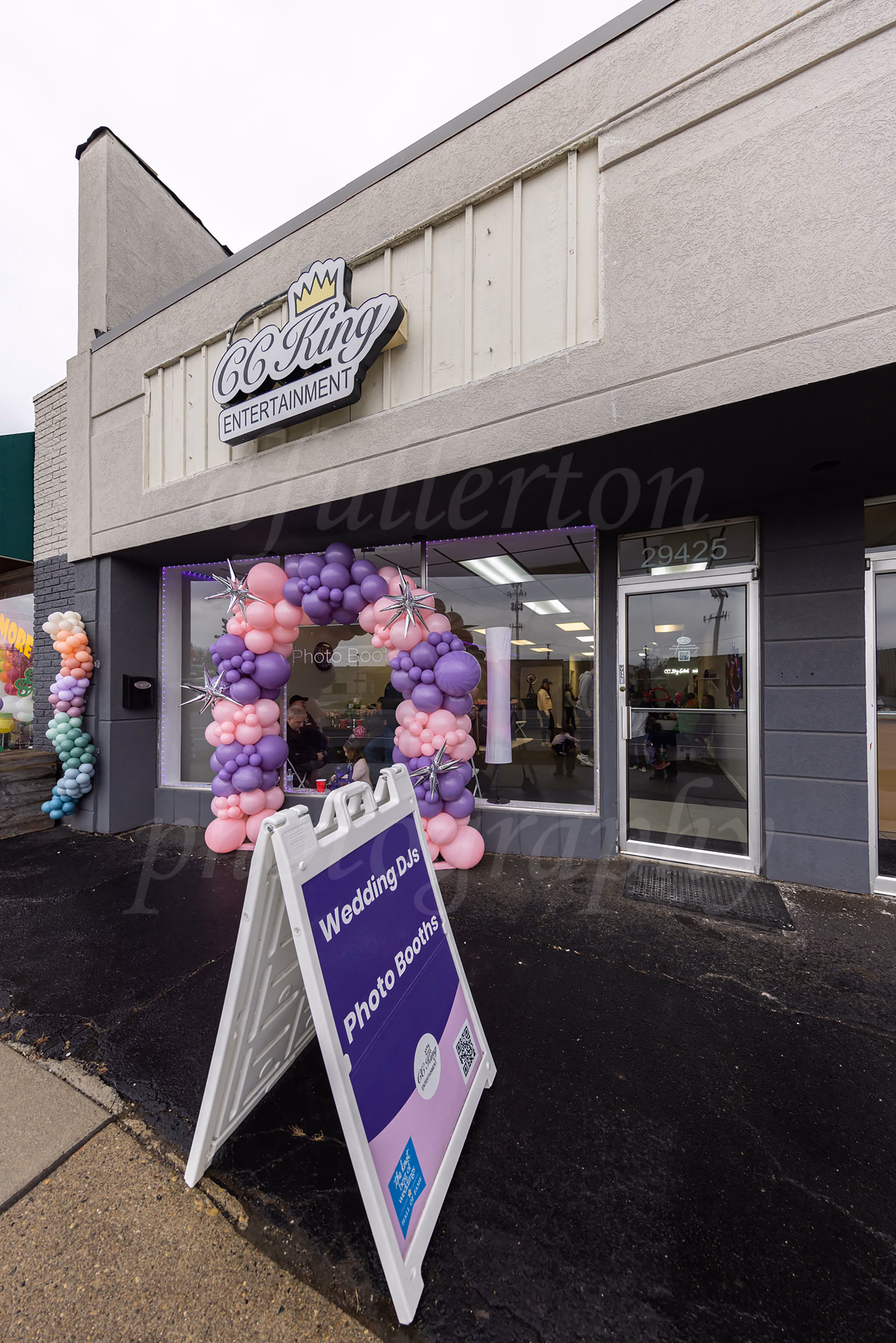 CC King Entertainment storefront with a balloon garland arch and sidewalk sign advertising wedding DJs and photo booths
