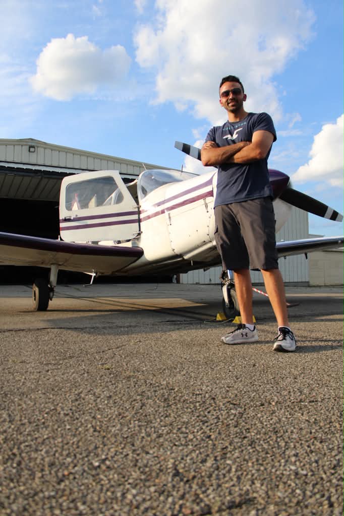 Ahmad Serhan, flight instructor, standing beside a Piper aircraft.