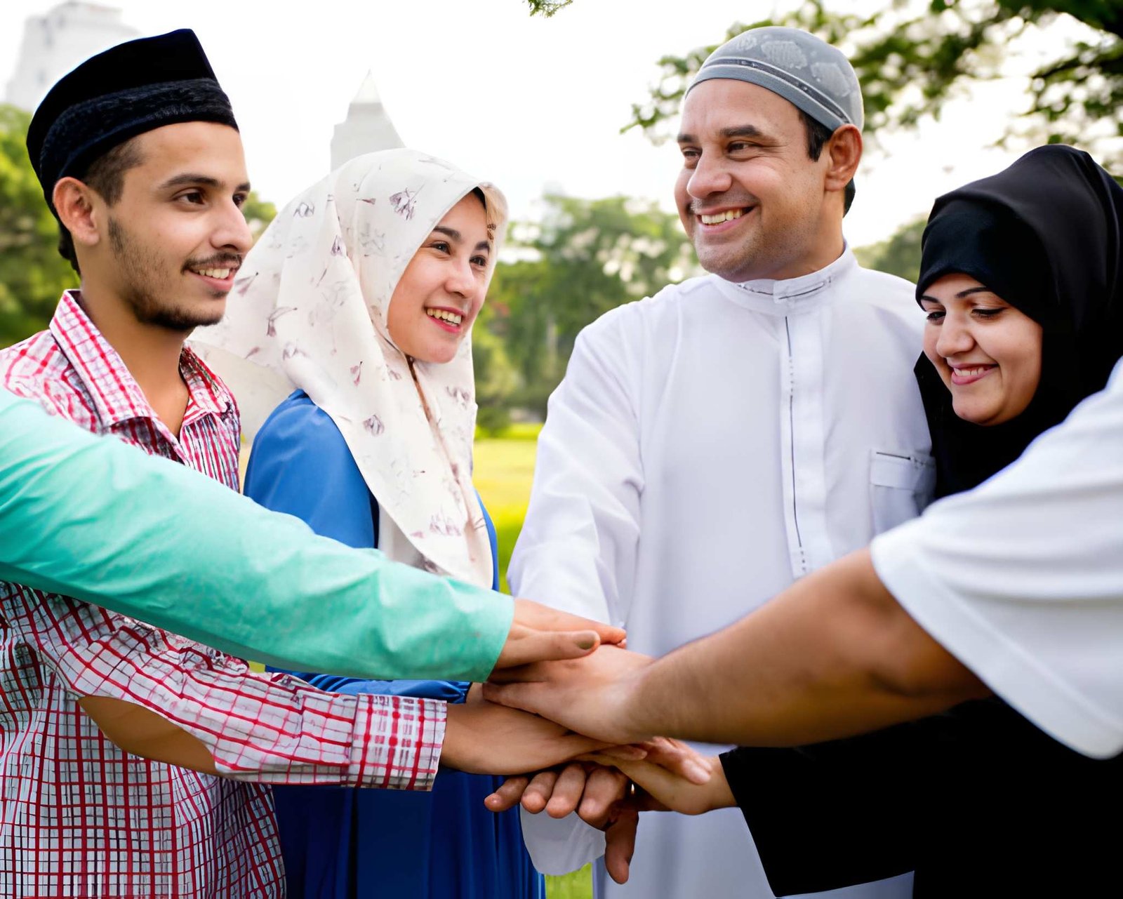 A group of smiling Muslim men and women putting their hands together in unity.