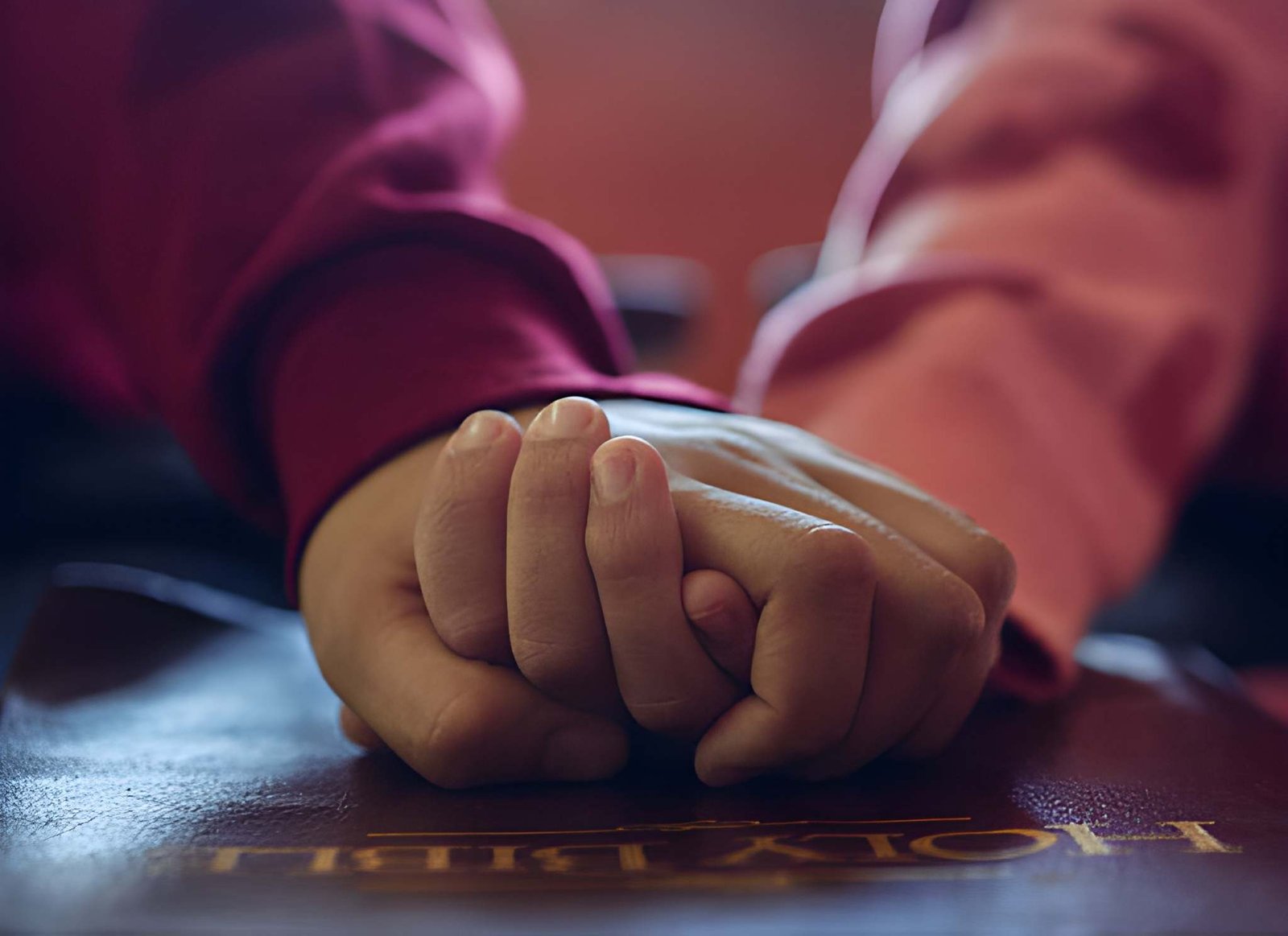 Two people holding hands over a book in a gesture of support and care.