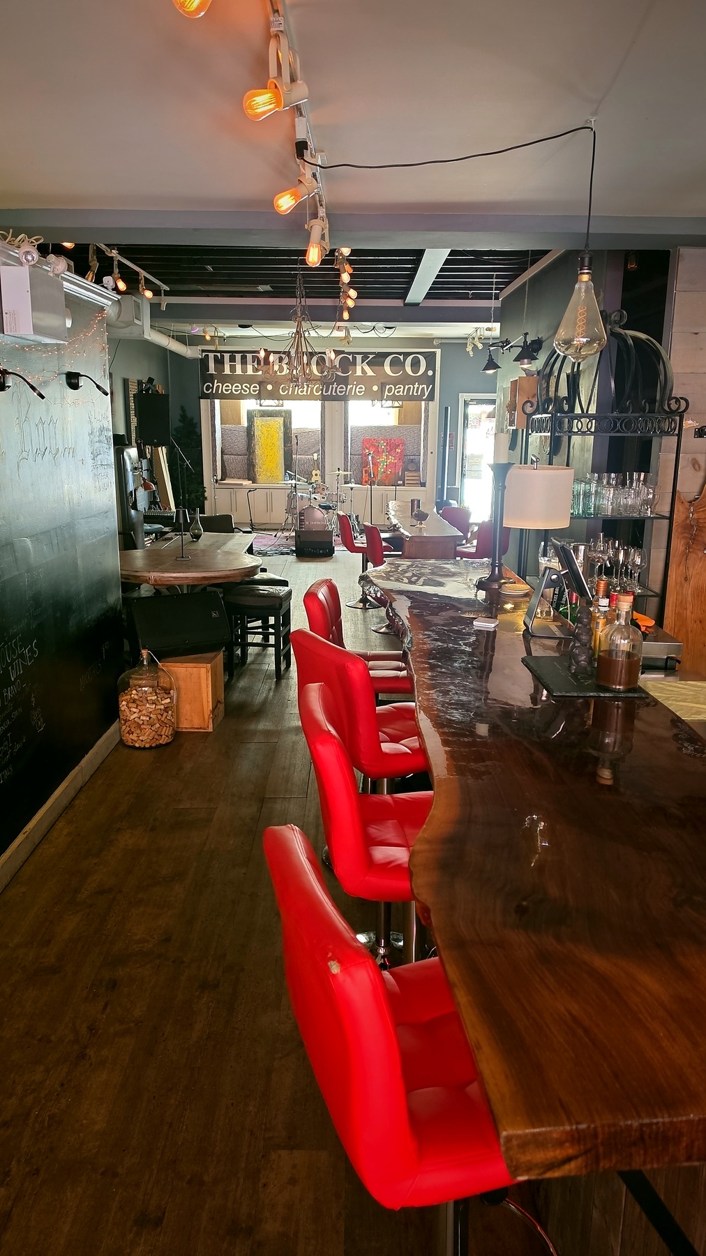 Live-edge wood bar and red leather stools inside The Block Co.