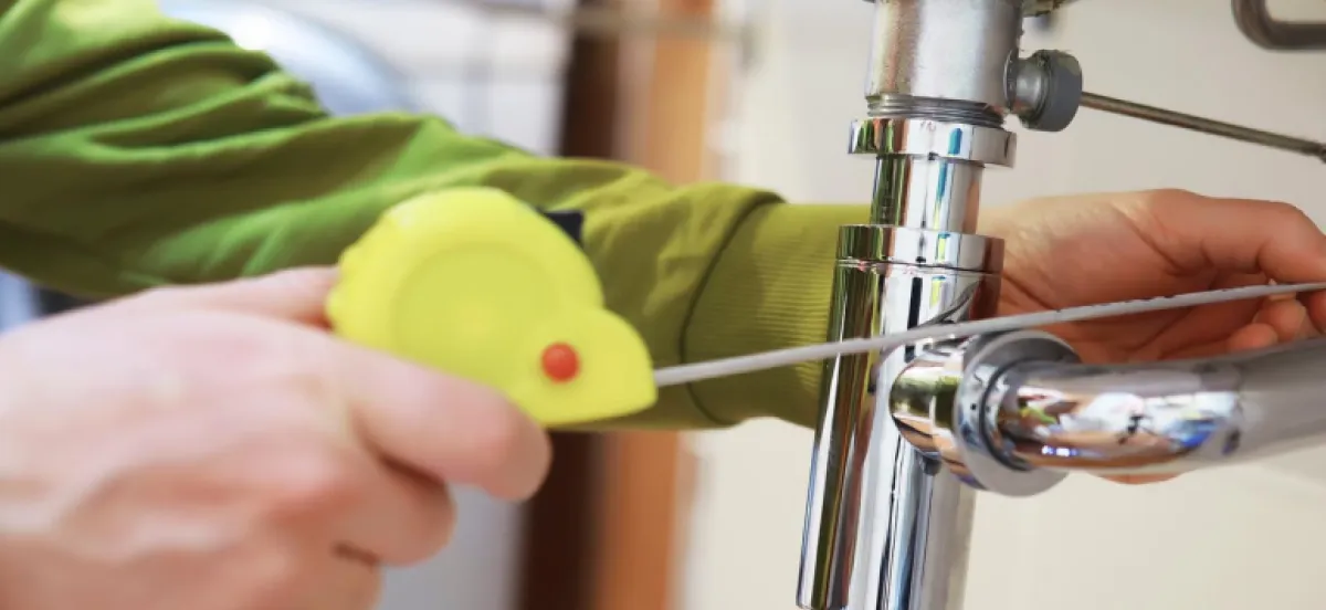 Technician running a drain snake through a sink pipe