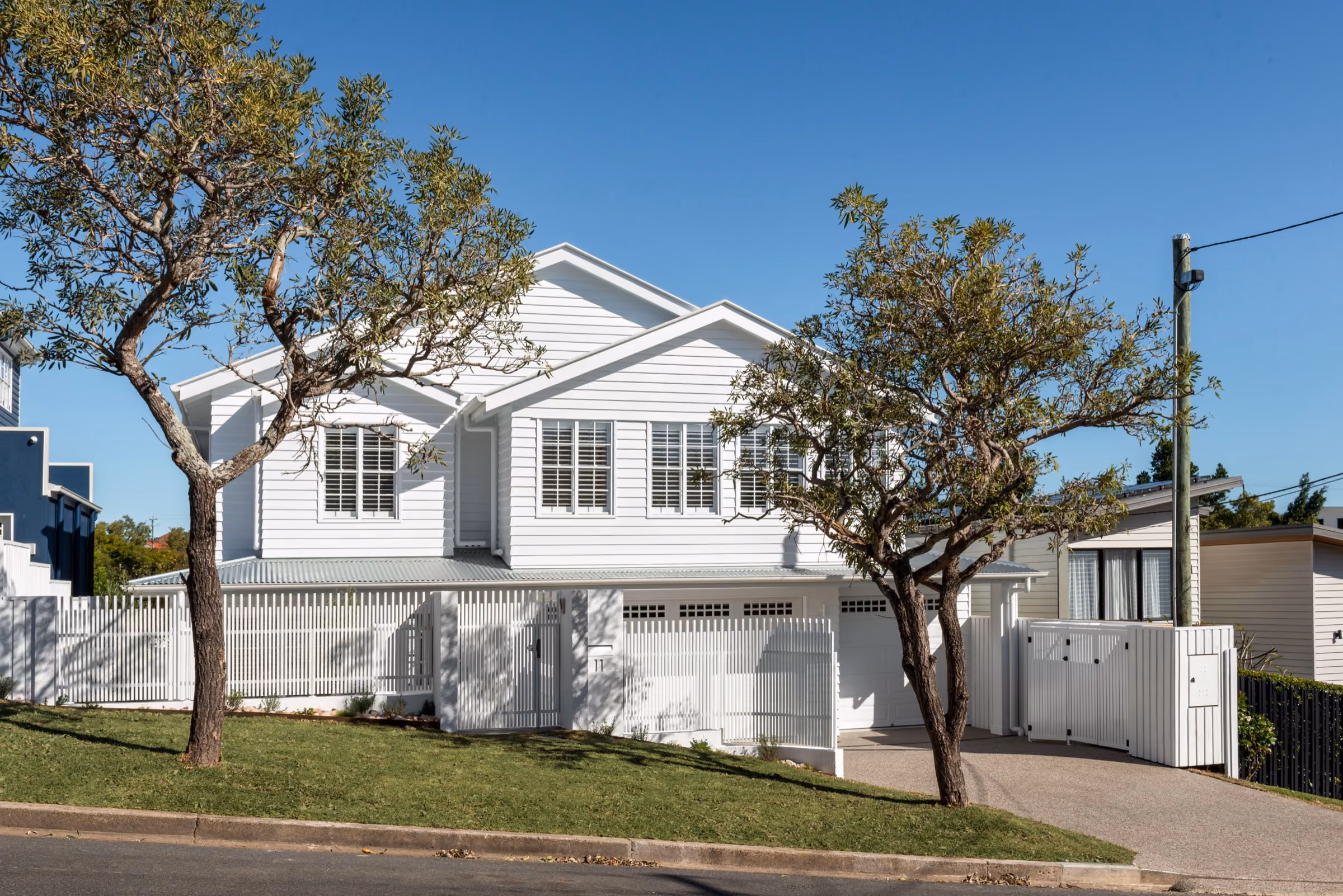 Completed white weatherboard home with mature street trees