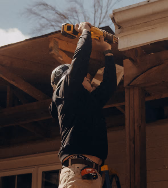 Contractor fitting timber trim on a roof overhang