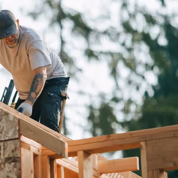 A contractor working on a timber roof frame