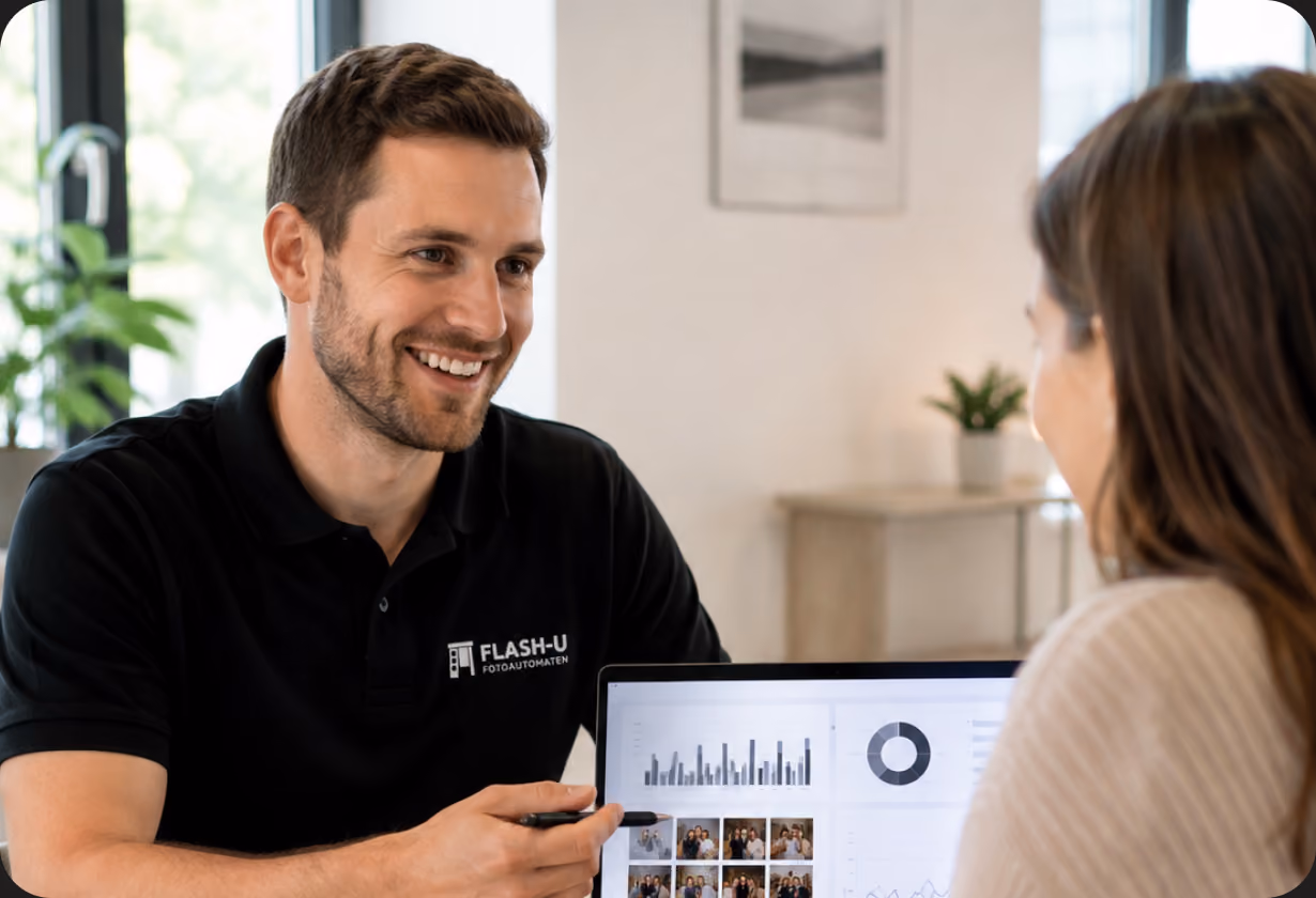 Lächelnder Mann und Frau besprechen Daten auf einem Laptop-Bildschirm in modernem Büro, Pflanzen im Hintergrund.