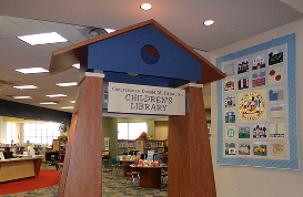 Entrance arch to a children's library in a public library with bookshelves and a quilt on the wall.