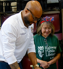Man wearing glasses and a white shirt stands next to a smiling woman in a Rahway Public Library shirt.