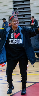 Smiling person wearing a black I Heart Cathedral sweatshirt and dark jacket with a headband selfie stick.