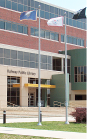 Entrance of Rahway Public Library with flags on poles and brick building exterior.