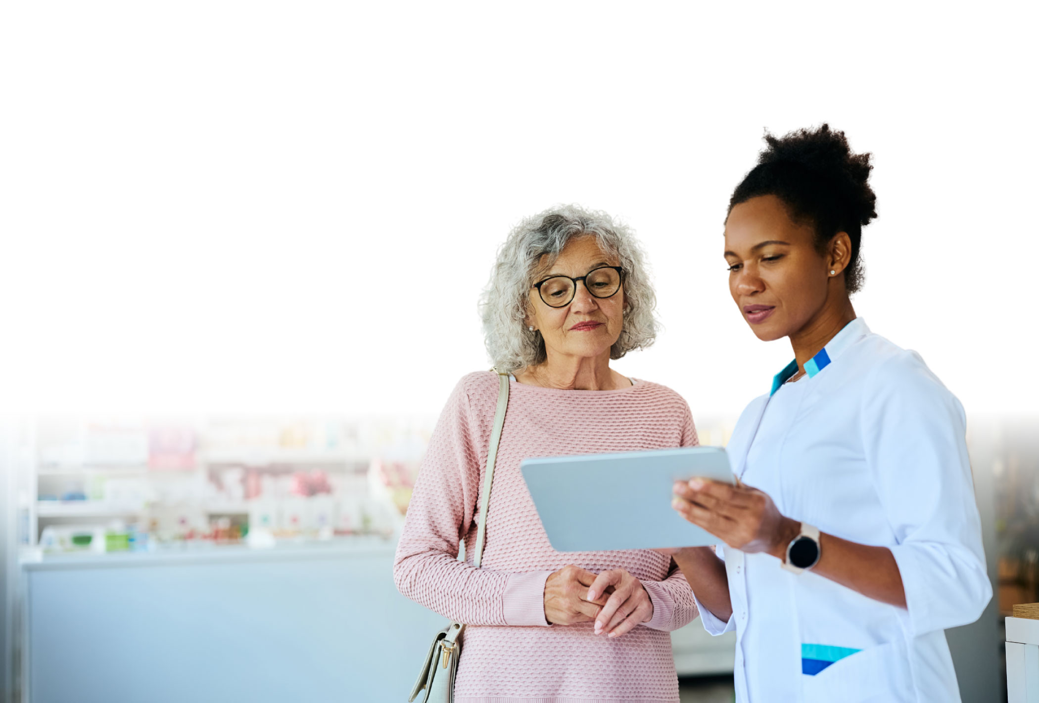 A Hometown Health System provider reviewing digital medical records on a tablet with a senior patient.