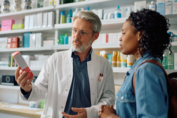 A pharmacist in a lab coat discussing medication options with a patient, representing Hometown Health System healthcare providers.