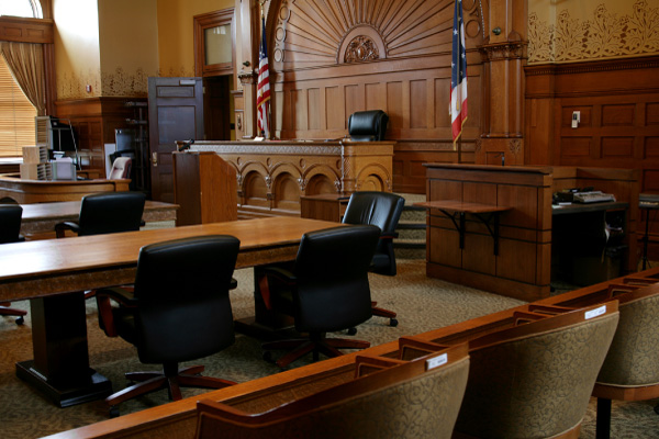 An empty courtroom with wooden benches and a judge's bench, representing Hometown Health System government and public health solutions.