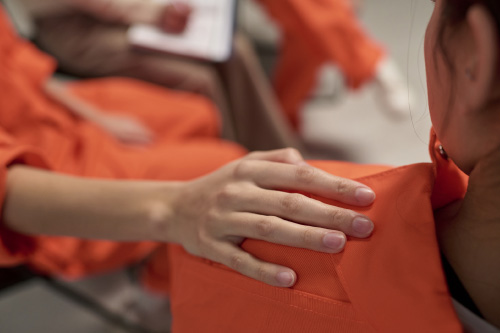 A supportive hand resting on the shoulder of a person in an orange correctional uniform, highlighting Hometown Health System's focus on stronger outcomes.