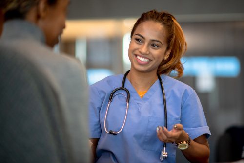 A smiling nurse in blue scrubs consulting with a patient to highlight Hometown Health System's seamless continuity of care.
