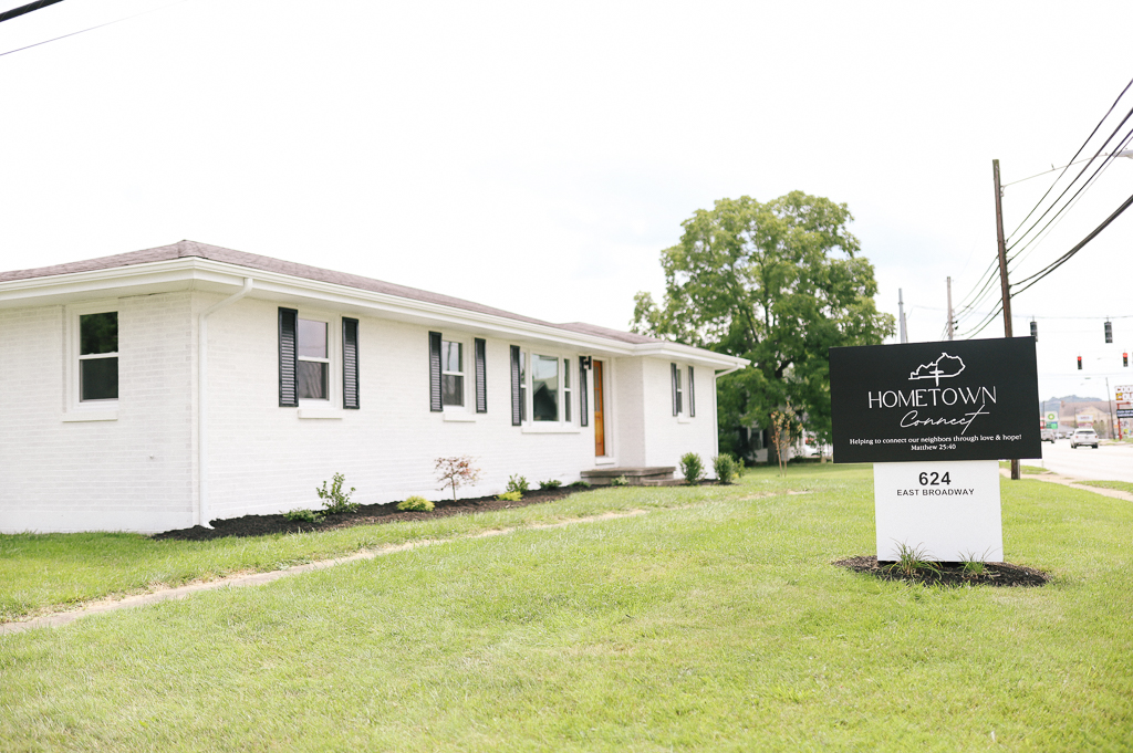 Exterior view of the Hometown Connect building, a white house with black shutters and signage on a grassy lawn.