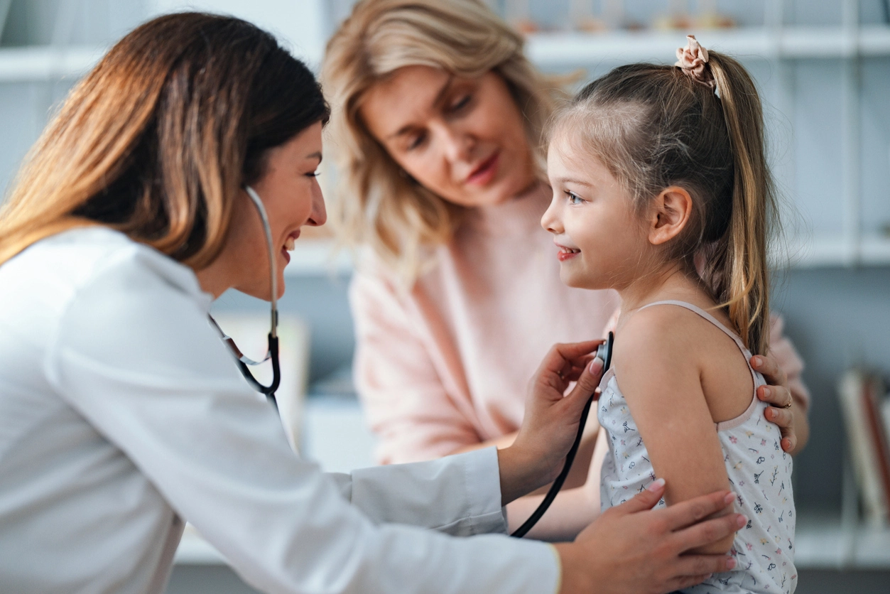Hero header banner titled "Frequently Asked Questions" showing a doctor using a stethoscope to examine a young patient.
