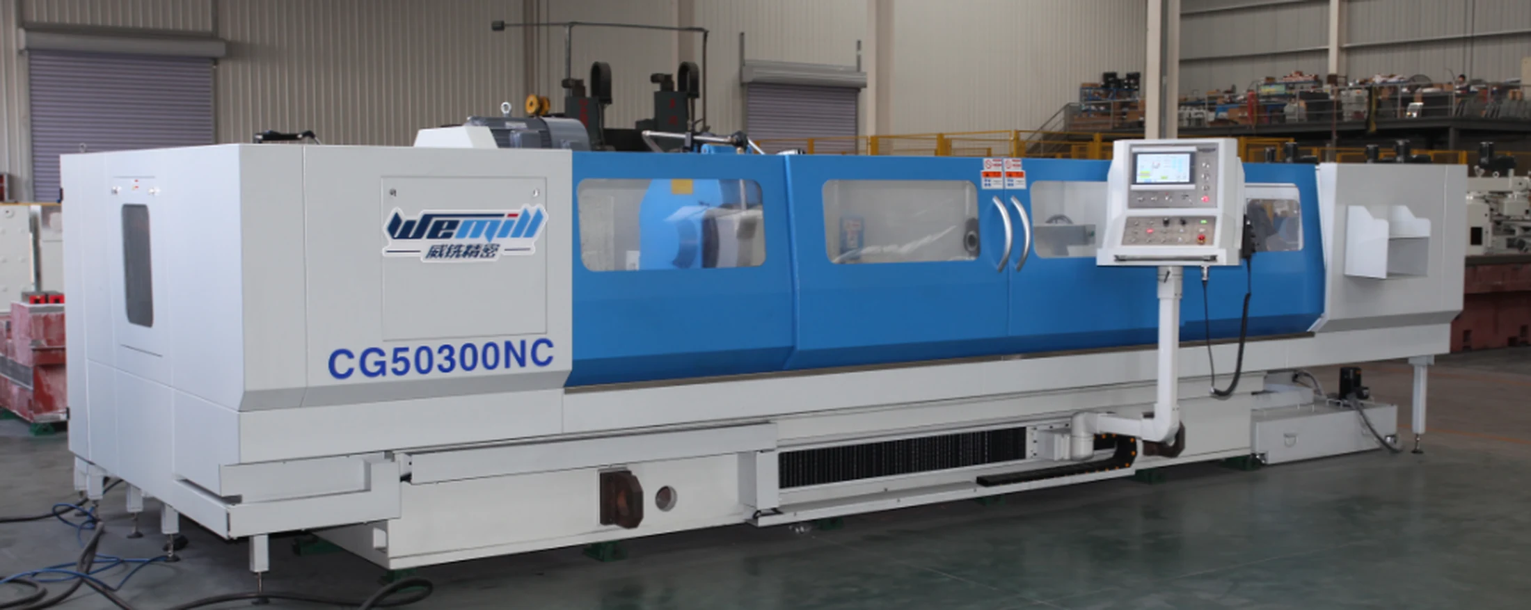 Original CG50300NC CNC cylindrical grinding machine in a factory, with white end covers, a blue central enclosure and a freestanding operator console.